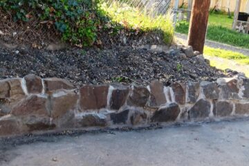 retaining wall constructed of locally sourced basalt rock for sloped garden area in The Dalles Oregon rental property driveway